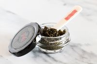 A tin of Caviar Co Royal white sturgeon caviar with a mother-of-pearl spoon inside