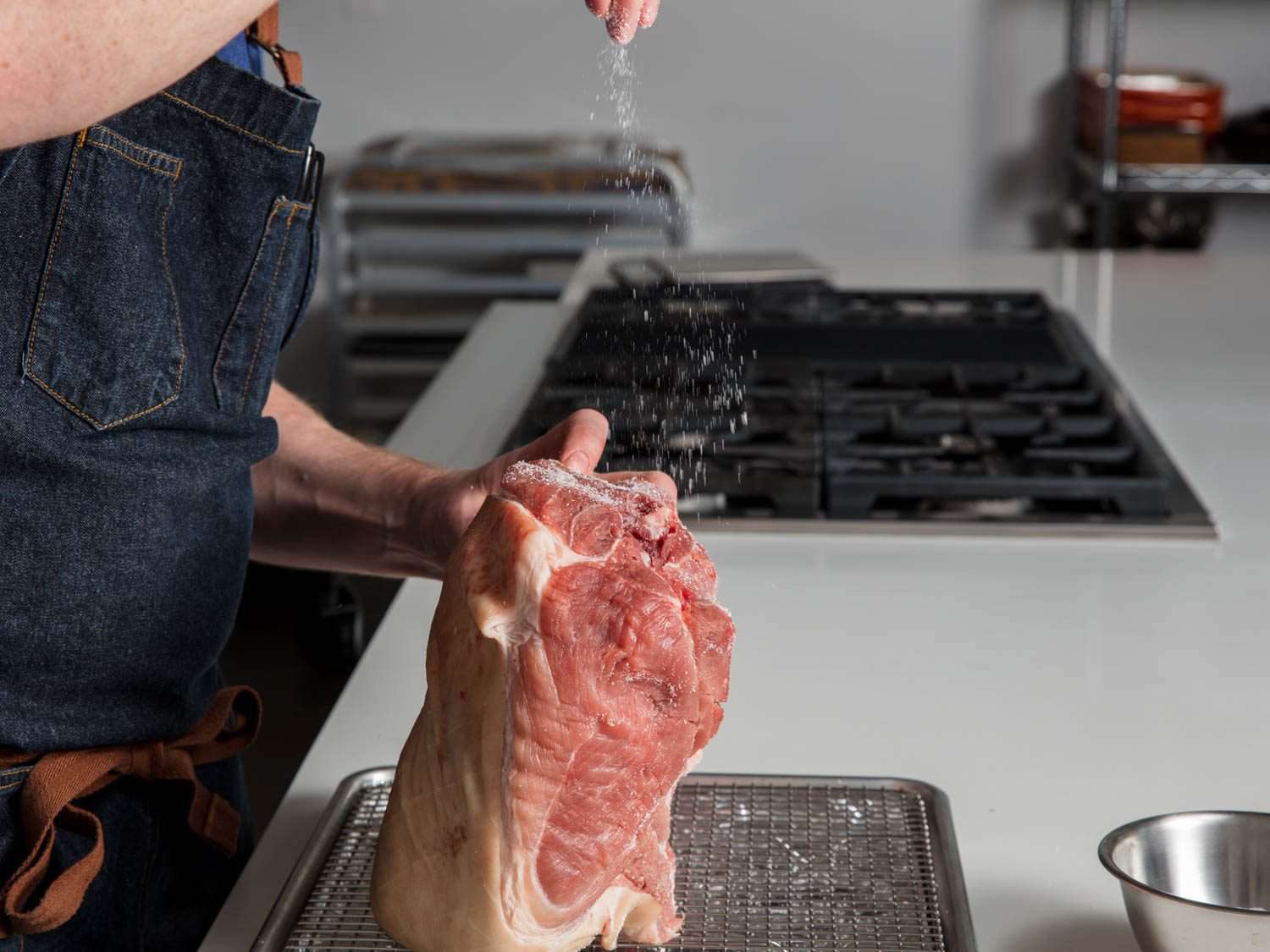 Seasoning a pork shoulder with salt.