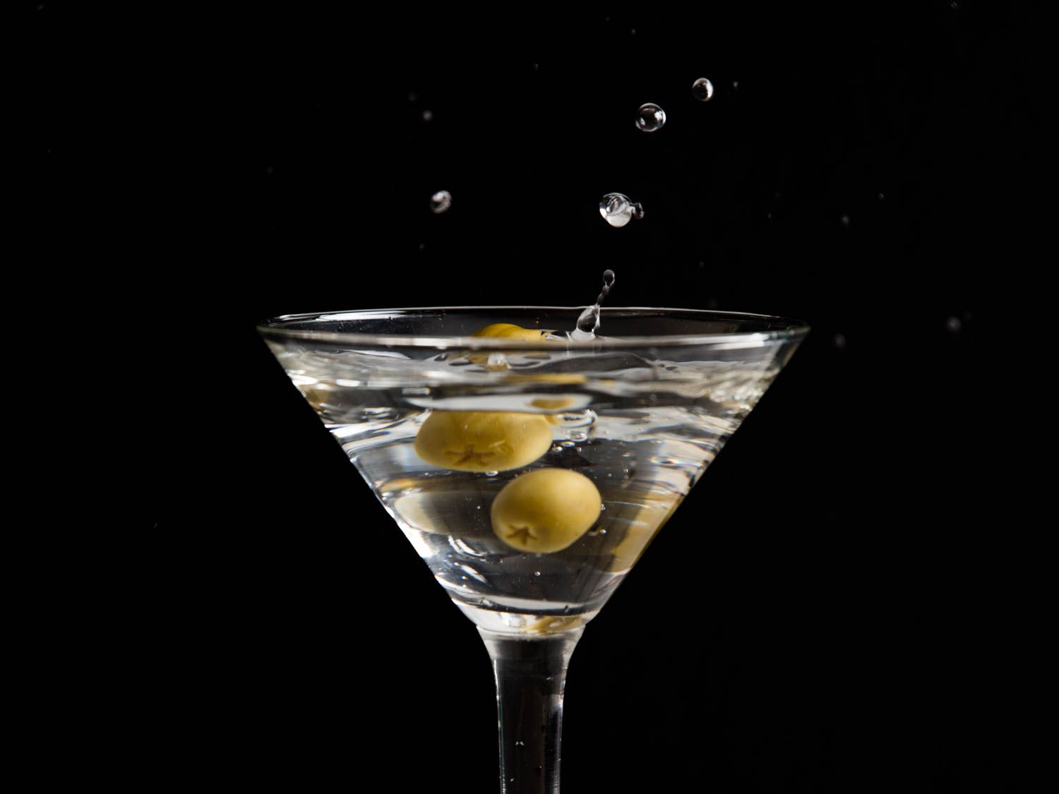 A glass of wet martini garnished with olives.