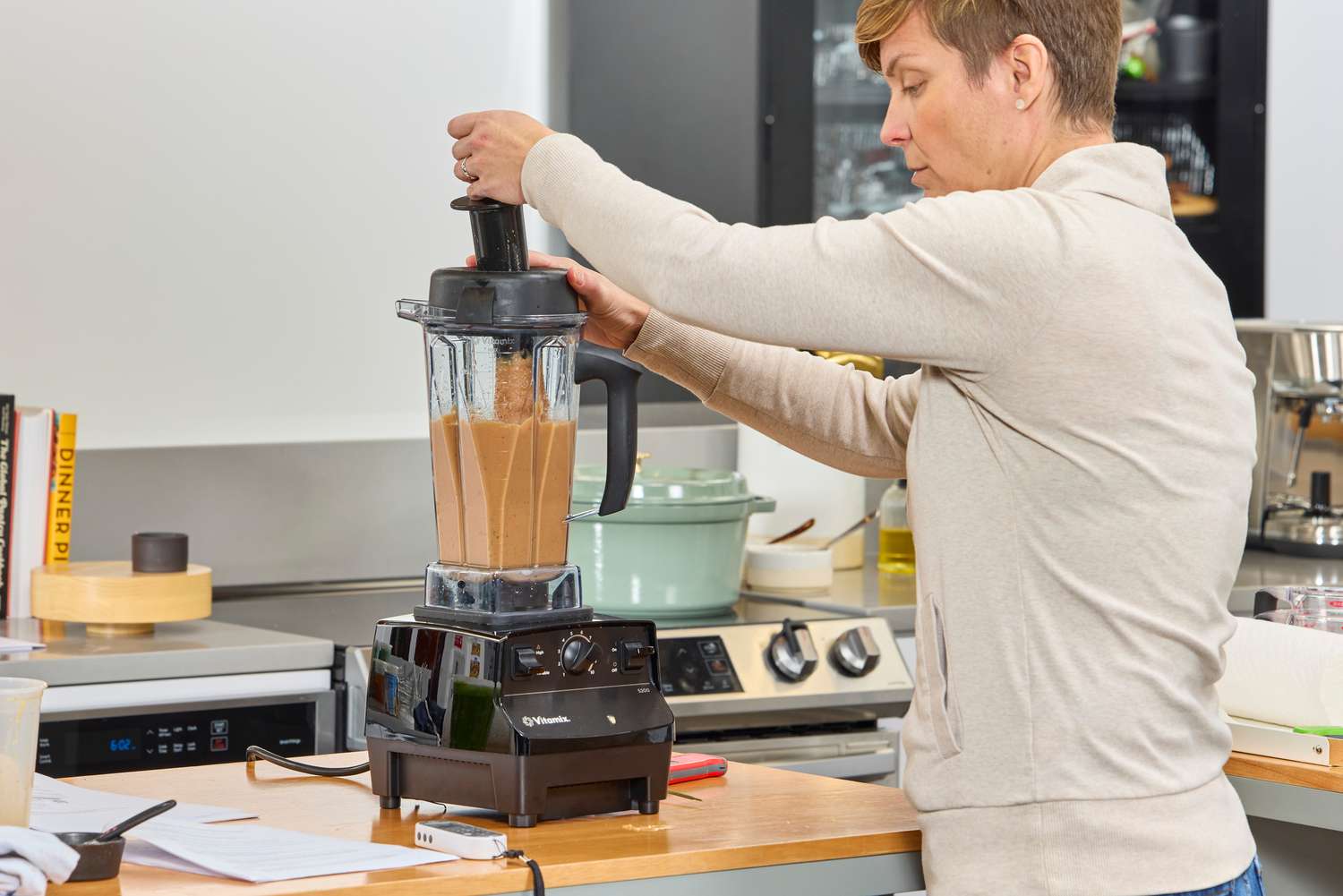 A person using a tool inside of the Vitamix 5200 Professional-Grade Blender to blend items better