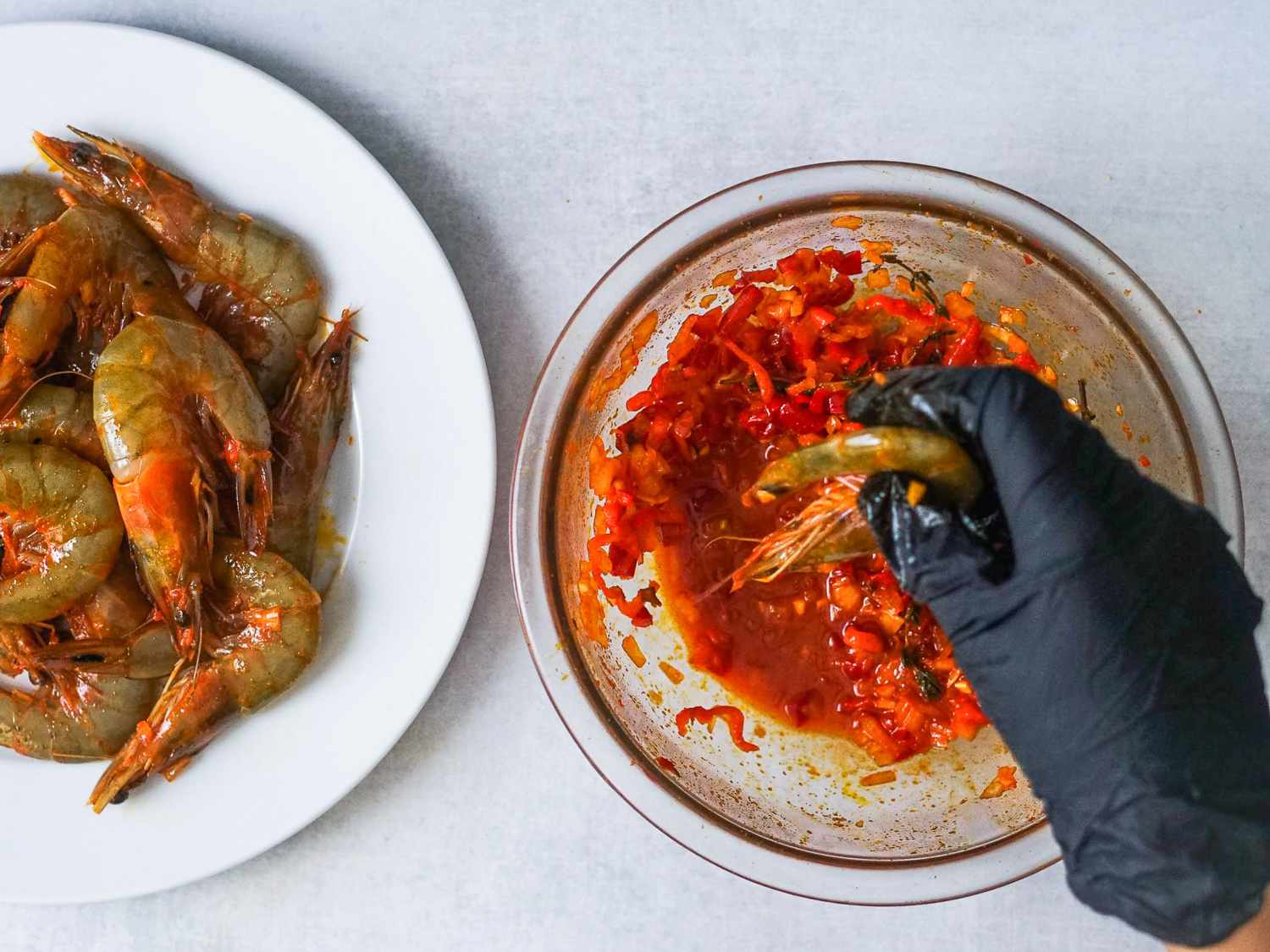 Shrimp being pulled from the marinade and placed on a plate.