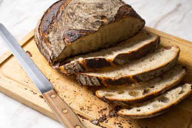 A round loaf of bread slices on a wooden cutting board.