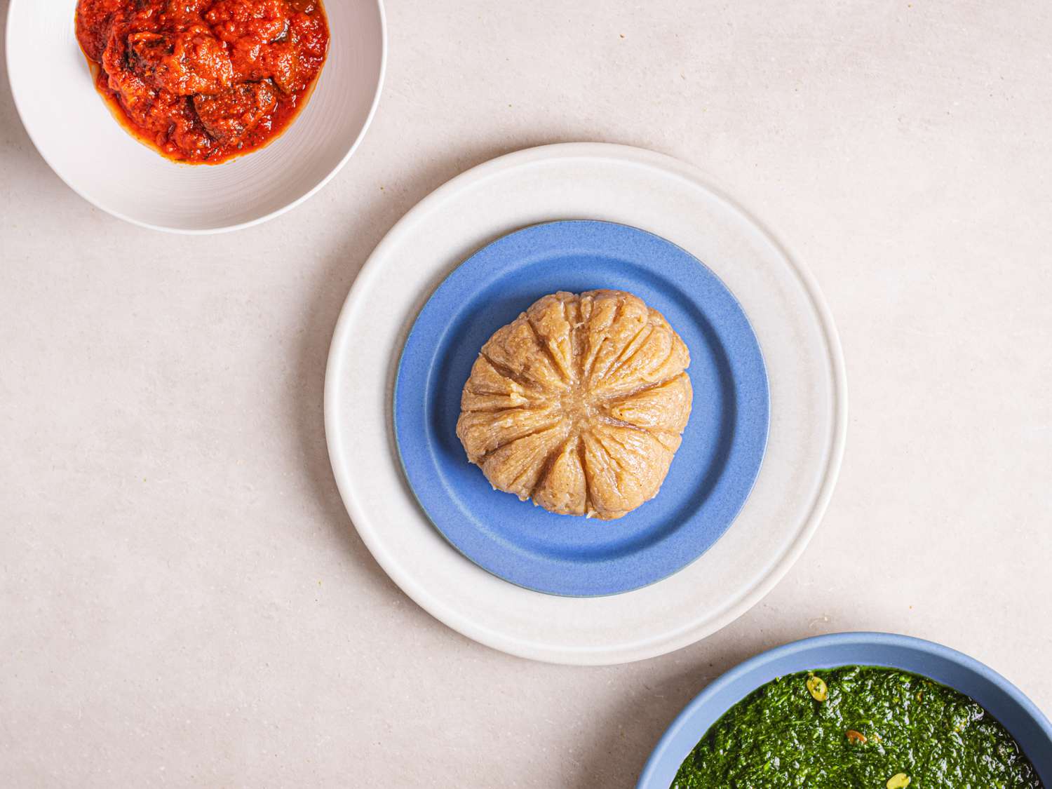 Overhead view of lafun, served with a greens soup and a bowl of obe ata (red pepper sauce).