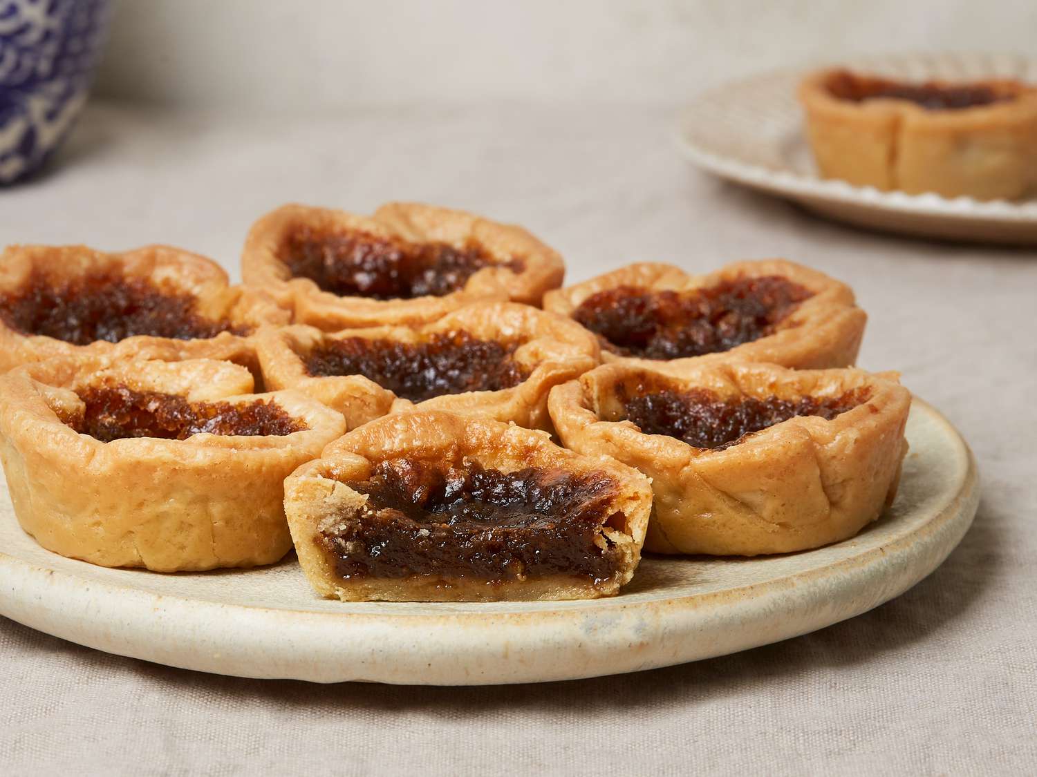 Plate of Canadian butter tarts, with one cut open and filling showing 