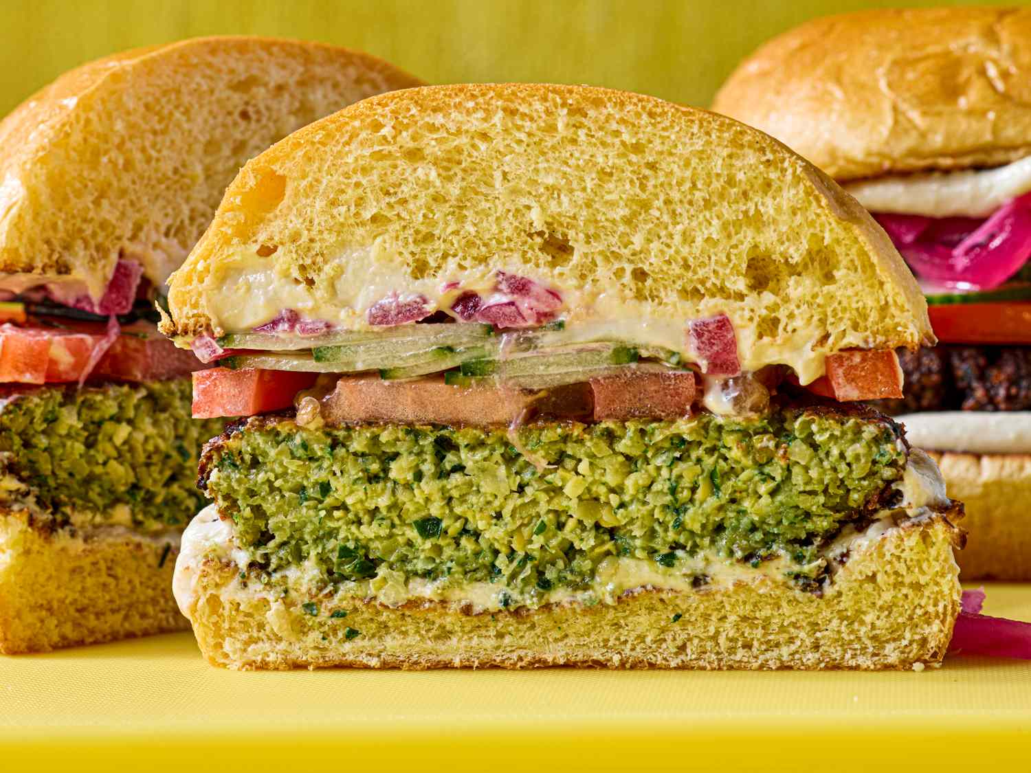 A sliced falafel burger with visible toppings including tomatoes and onions