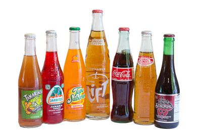 7 bottles of Mexican sodas, lined up on a white background
