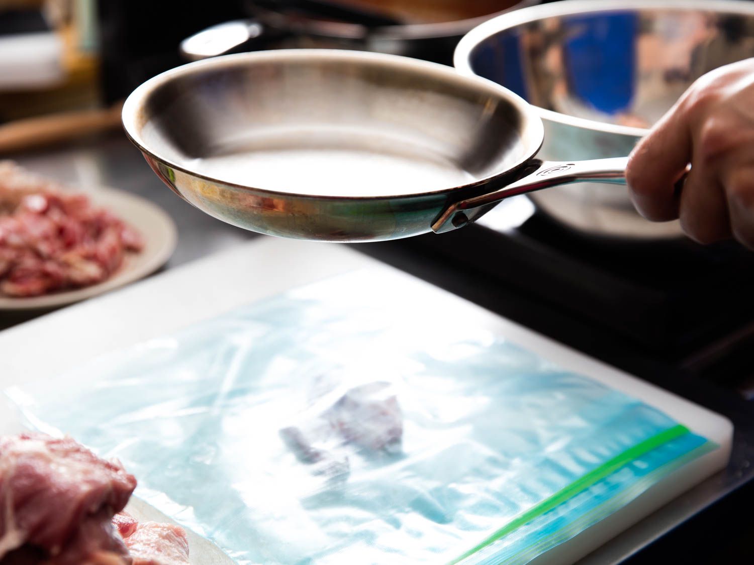 Sliced pork is pounded into thin cutlets in a split zipper-lock bag with an 8 inch skillet.