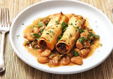 A plate of Sweet Potato and Mushroom Cannelloni, served atop Braised Escarole and Butter Beans.