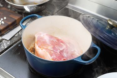 the le creuset dutch oven with a piece of pork shoulder searing in it. 
