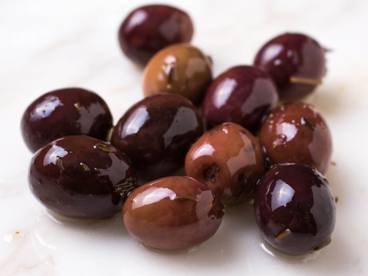 Closeup of pile of small, shiny olives in various shades of black and brown