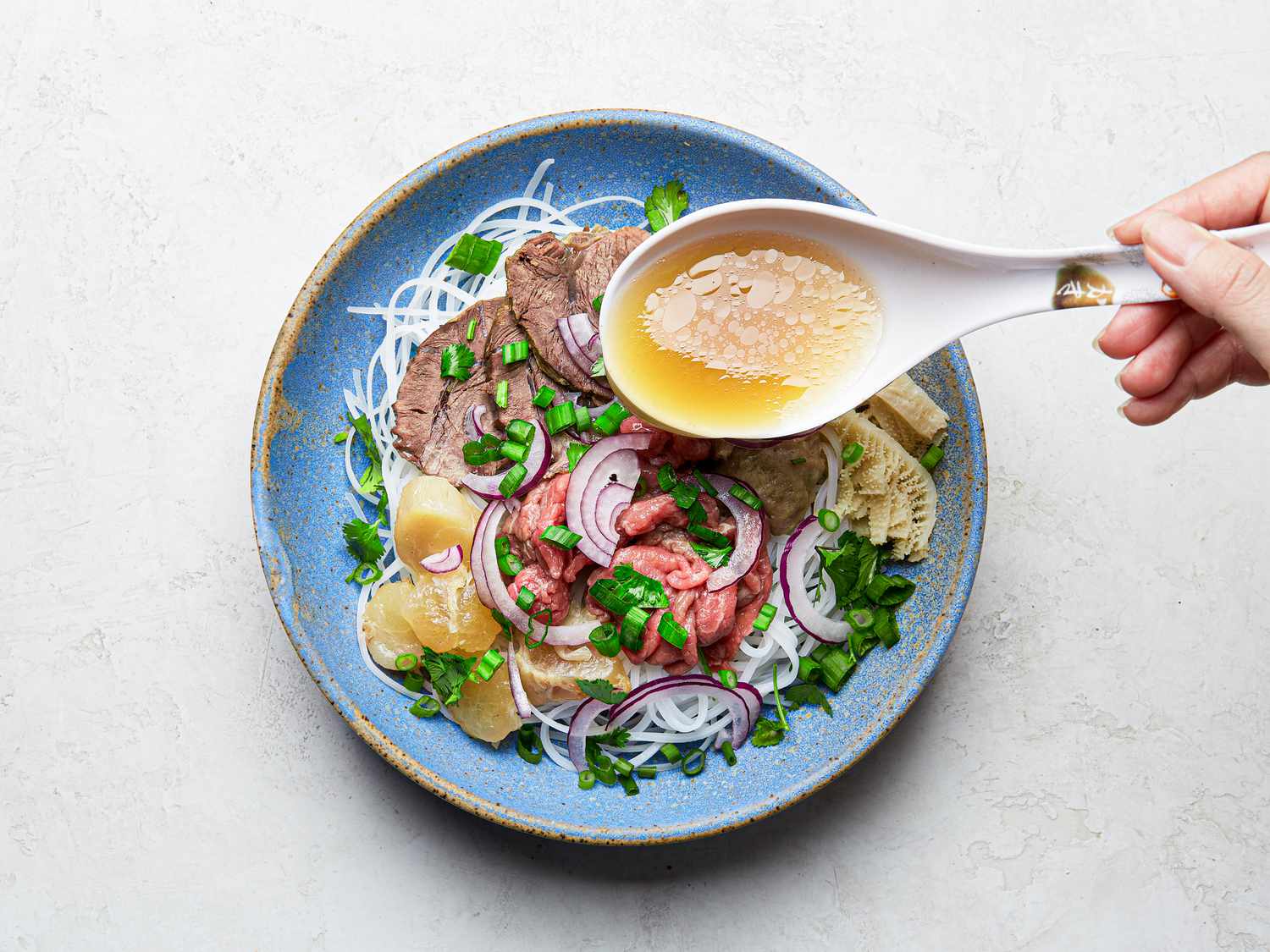 Overhead view of adding broth to pho