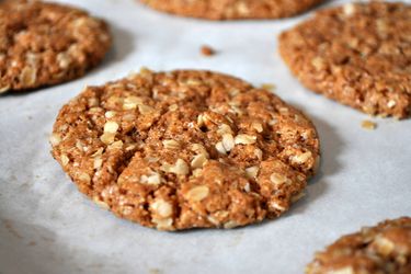 Closeup of crunchy almond butter oatmeal cookies on a parchment lined baking sheet, fresh from the oven.