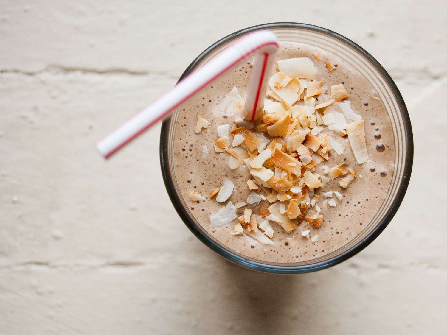 A coffee, banana, and hazelnut shake in a glass with a straw.
