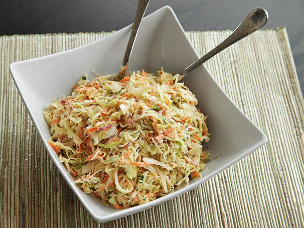 Crunchy, creamy homemade coleslaw in a square white bowl with serving utensils. 