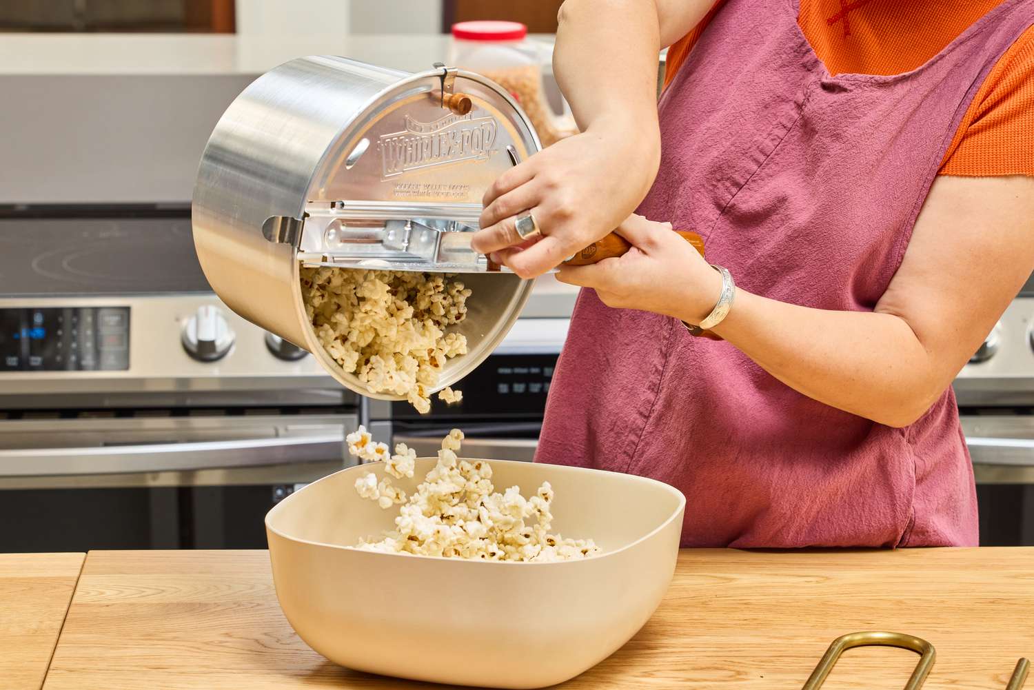 A person pours popcorn made in the Wabash Valley Farms Original Whirley-Pop Popcorn Popper into a bowl