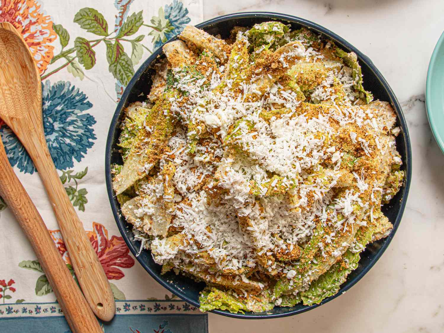 A bowl of feta and zaatar Caesar salad on a table with a floral tablecloth