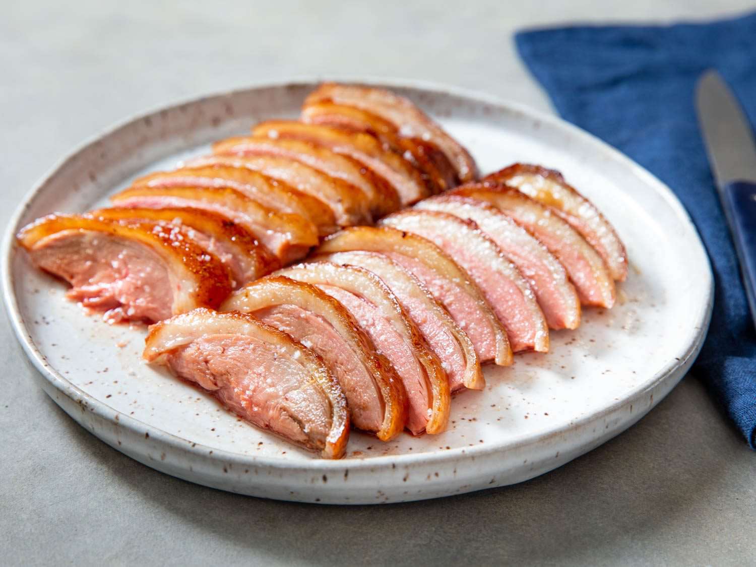 Side view of sliced soy-maltose roast duck breast on a serving platter.