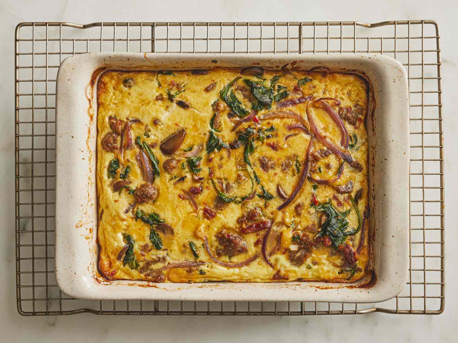 Baked casserole in a baking dish on a cooling rack.
