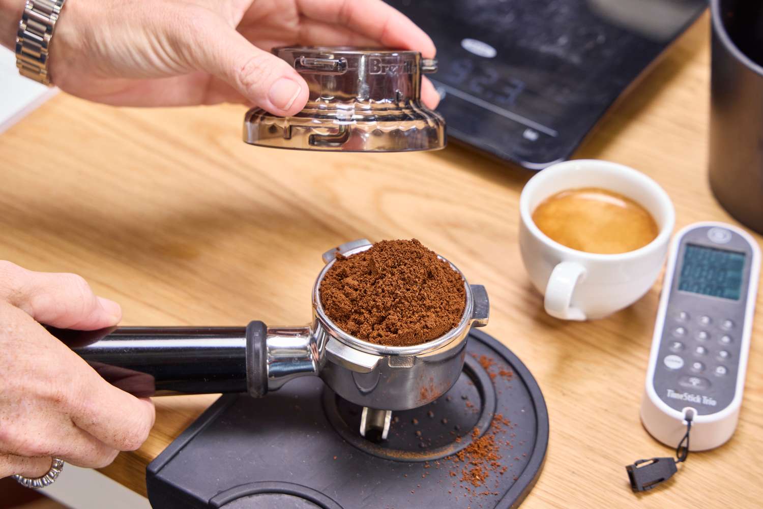 A person adds ground espresso beans to the portafilter before brewing in the Breville The Barista Express Espresso Machine