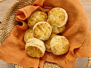 sour cream and chive biscuits in a basket with an orange napkin