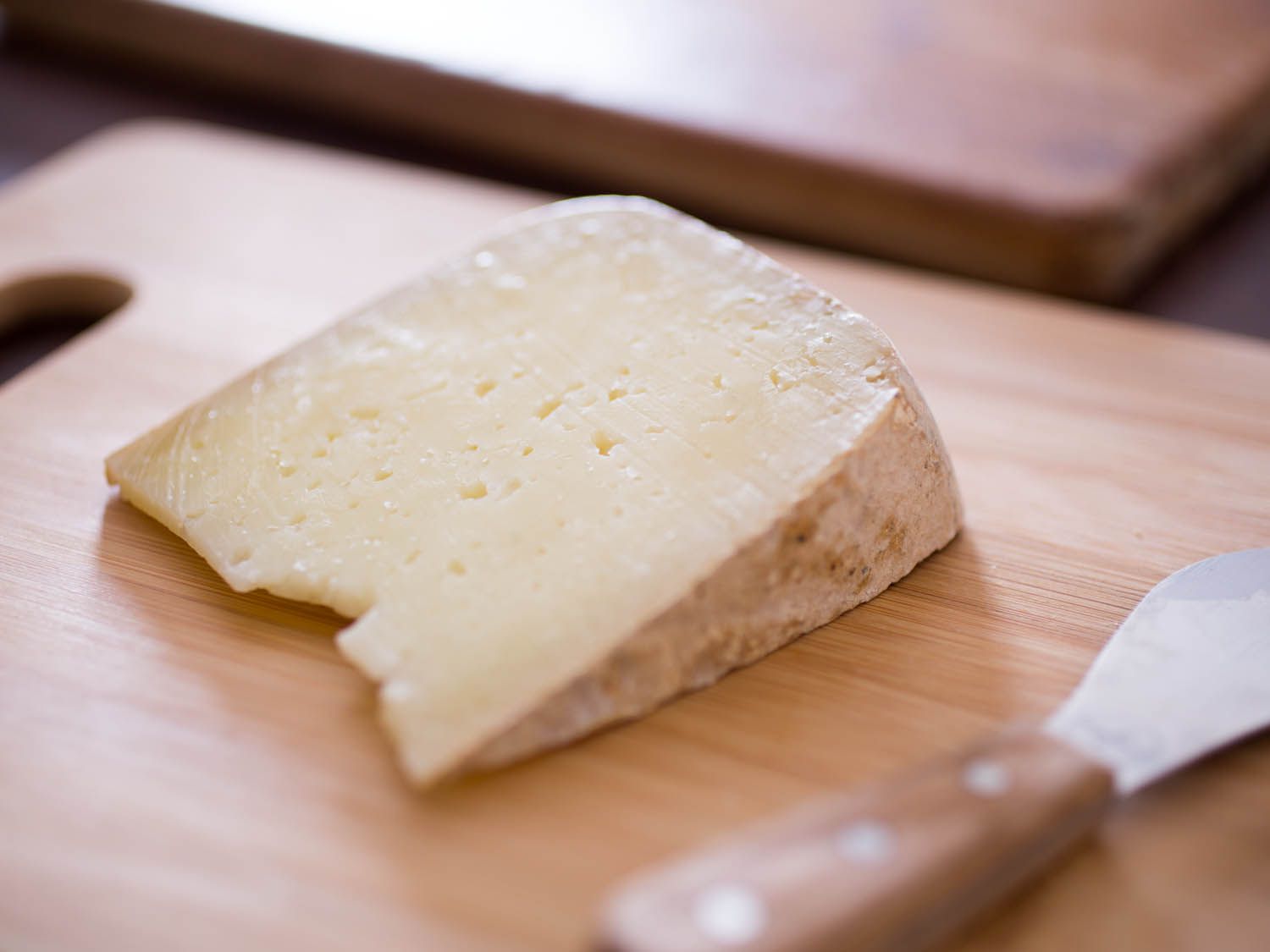 A wedge of Pyrénées sheep cheese on a cutting board.