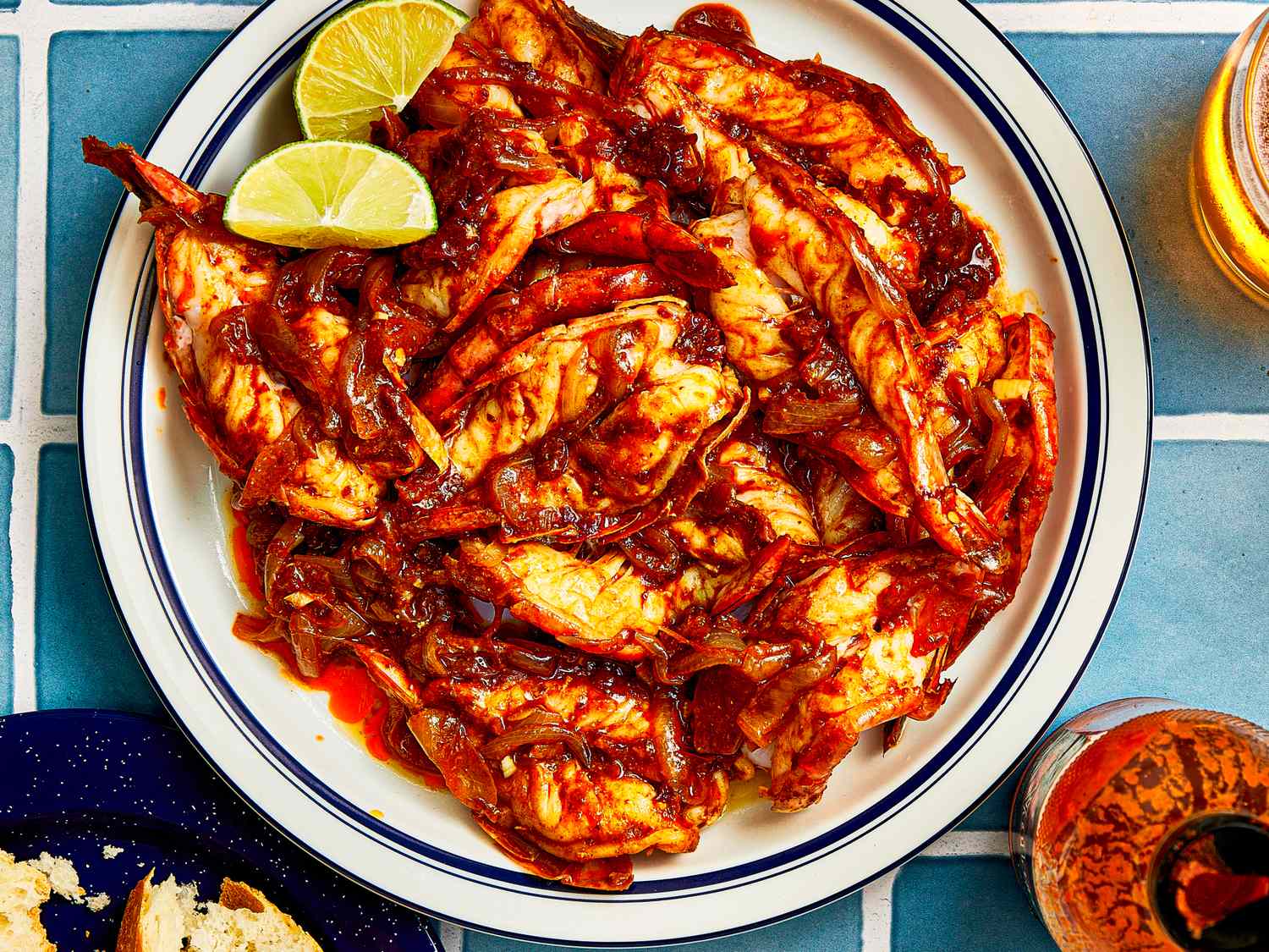A plate of camarones a la diabla garnished with lime wedges and placed on a tiled surface