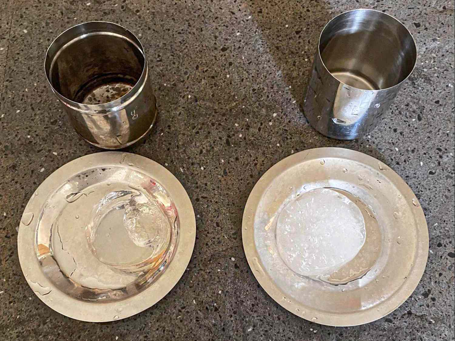 Two steel cups and plates displaying ice and clear circles on a textured surface