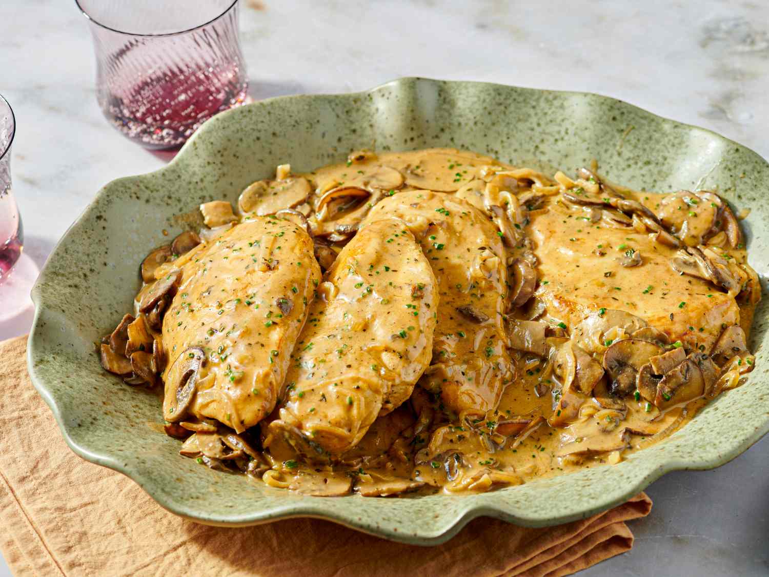 A dish of chicken fricassee garnished with herbs and served with mushrooms on a green plate