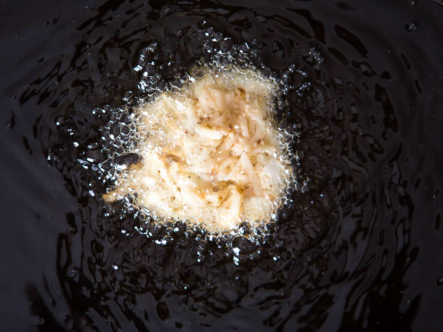 A latke being fried in oil.