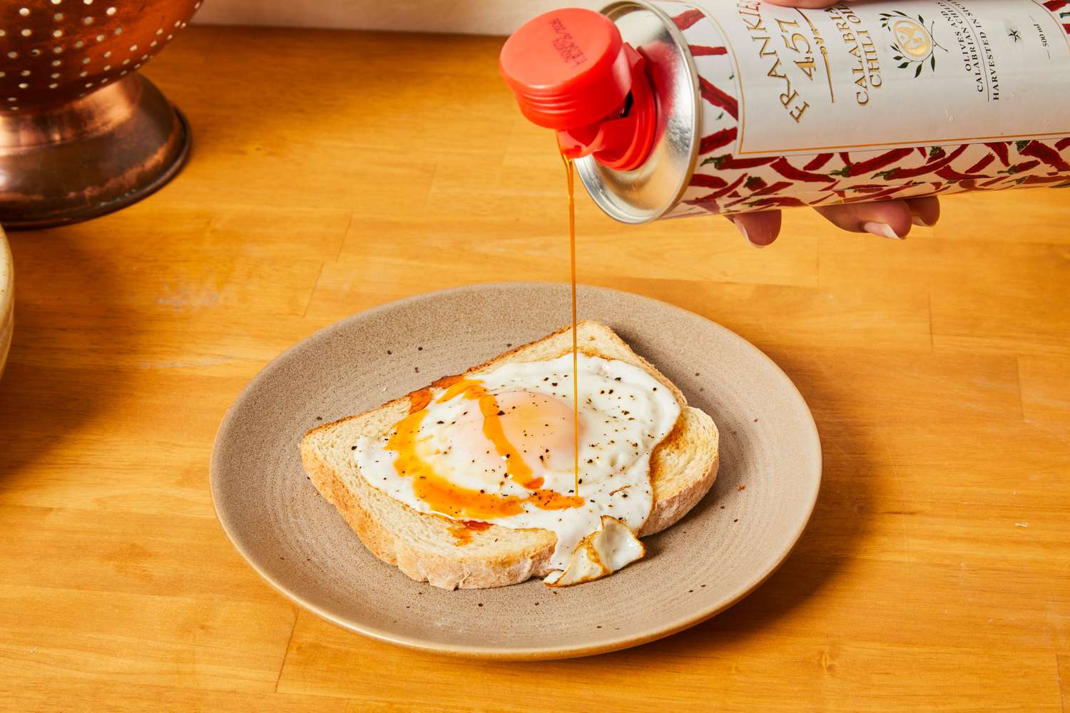 Chili olive oil being drizzled onto a fried egg on toast.