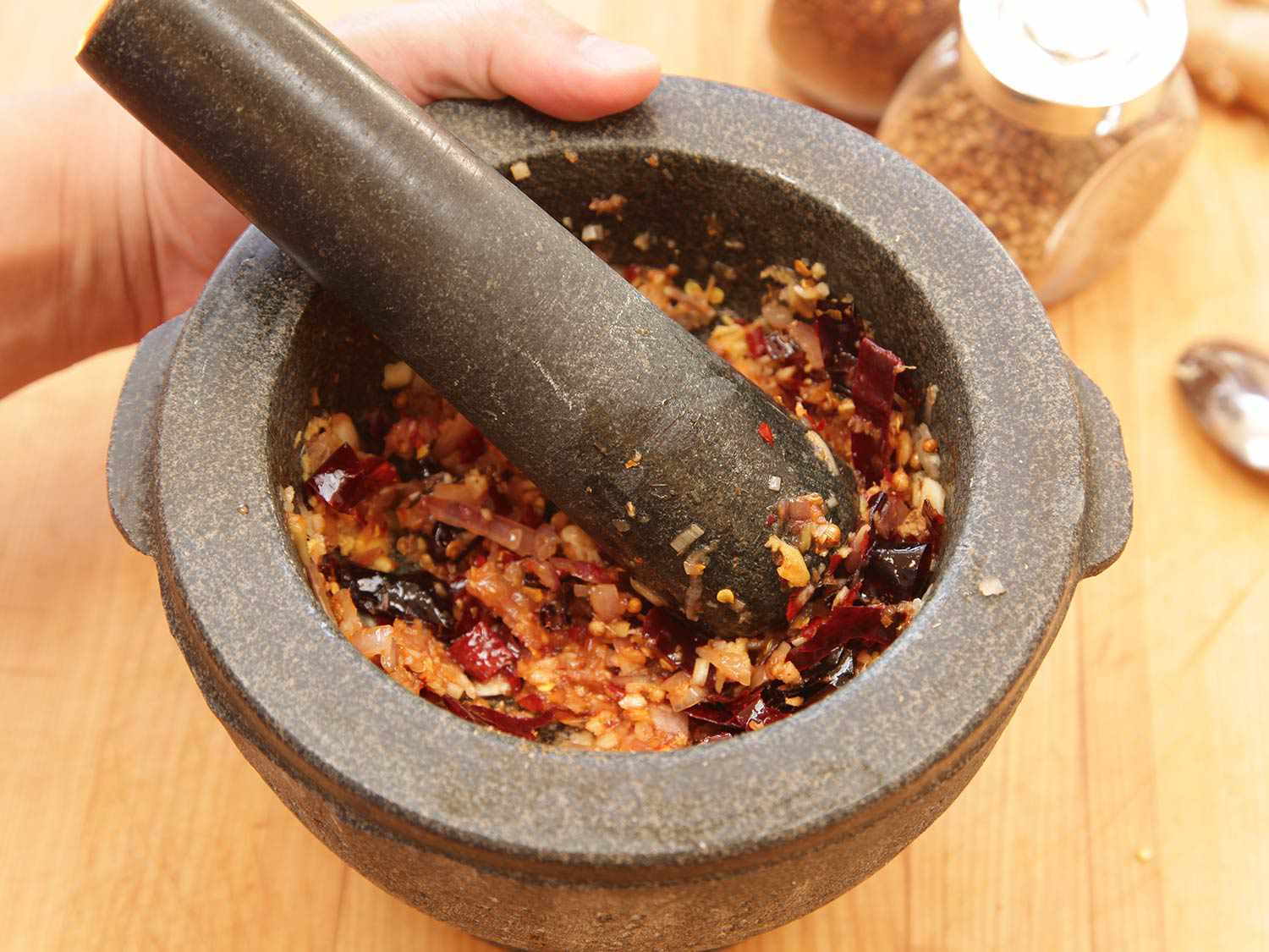 Pounding spice paste for satay in a pestle and mortar.