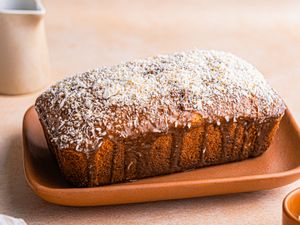 A loaf of banana coconut cake on a platter topped with shredded coconut
