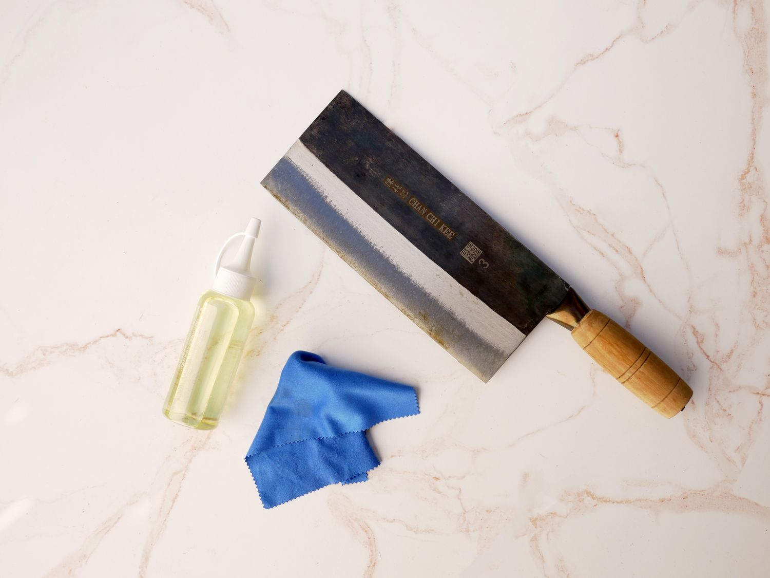 Chinese cleaver on marble surface with tsubaki oil and cloth