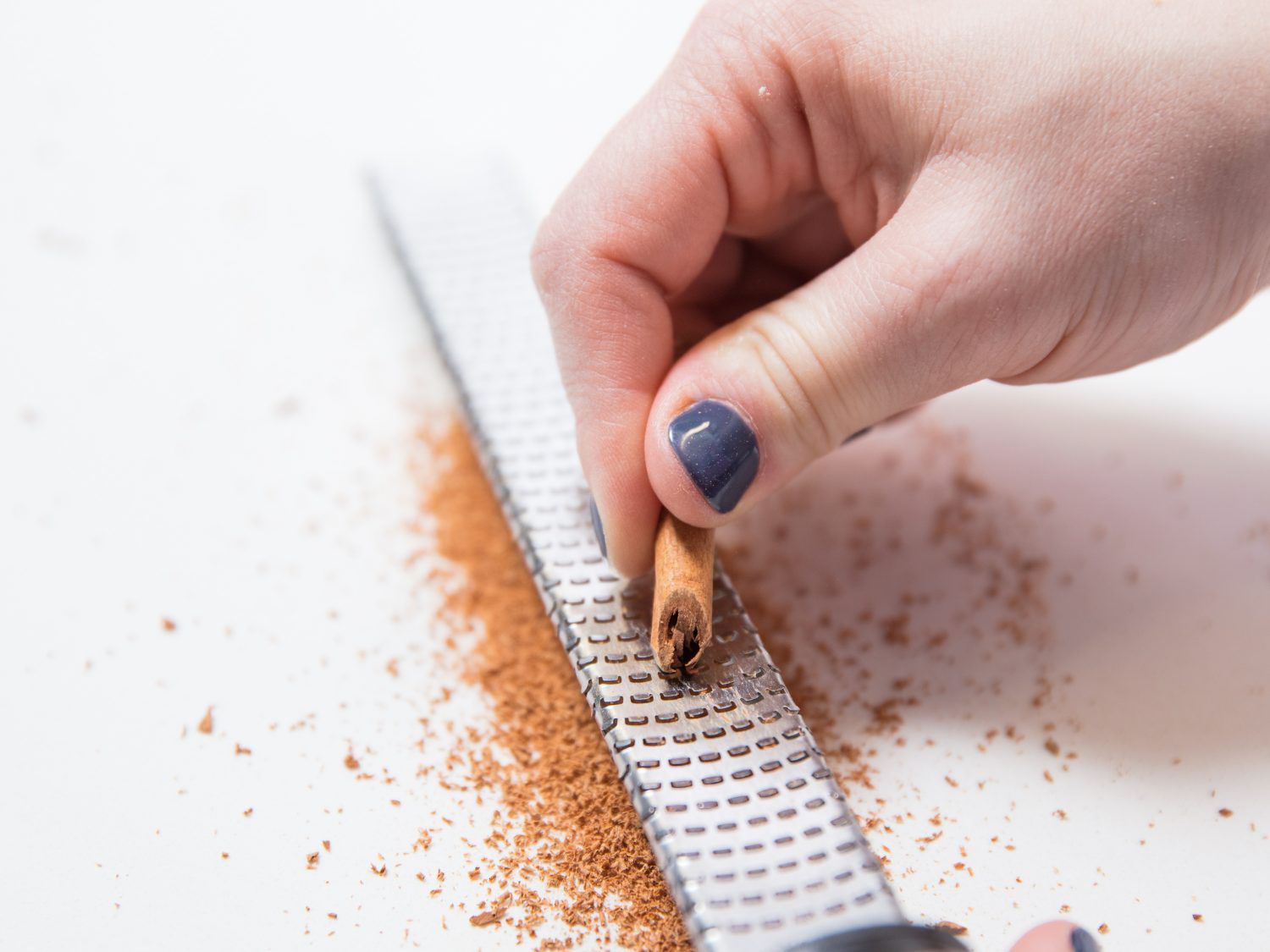 Grating a stick of cinnamon on a Microplane. 