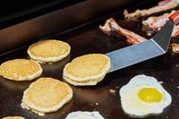 A person cooks pancakes on the Traeger Flatrock Flat Top Grill