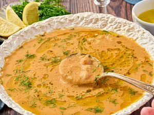 A bowl of chickpea stew garnished with herbs and oil served in a decorative plate