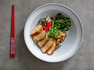 Overhead view of chicken donburi with spinach, served in a ceramic bowl.