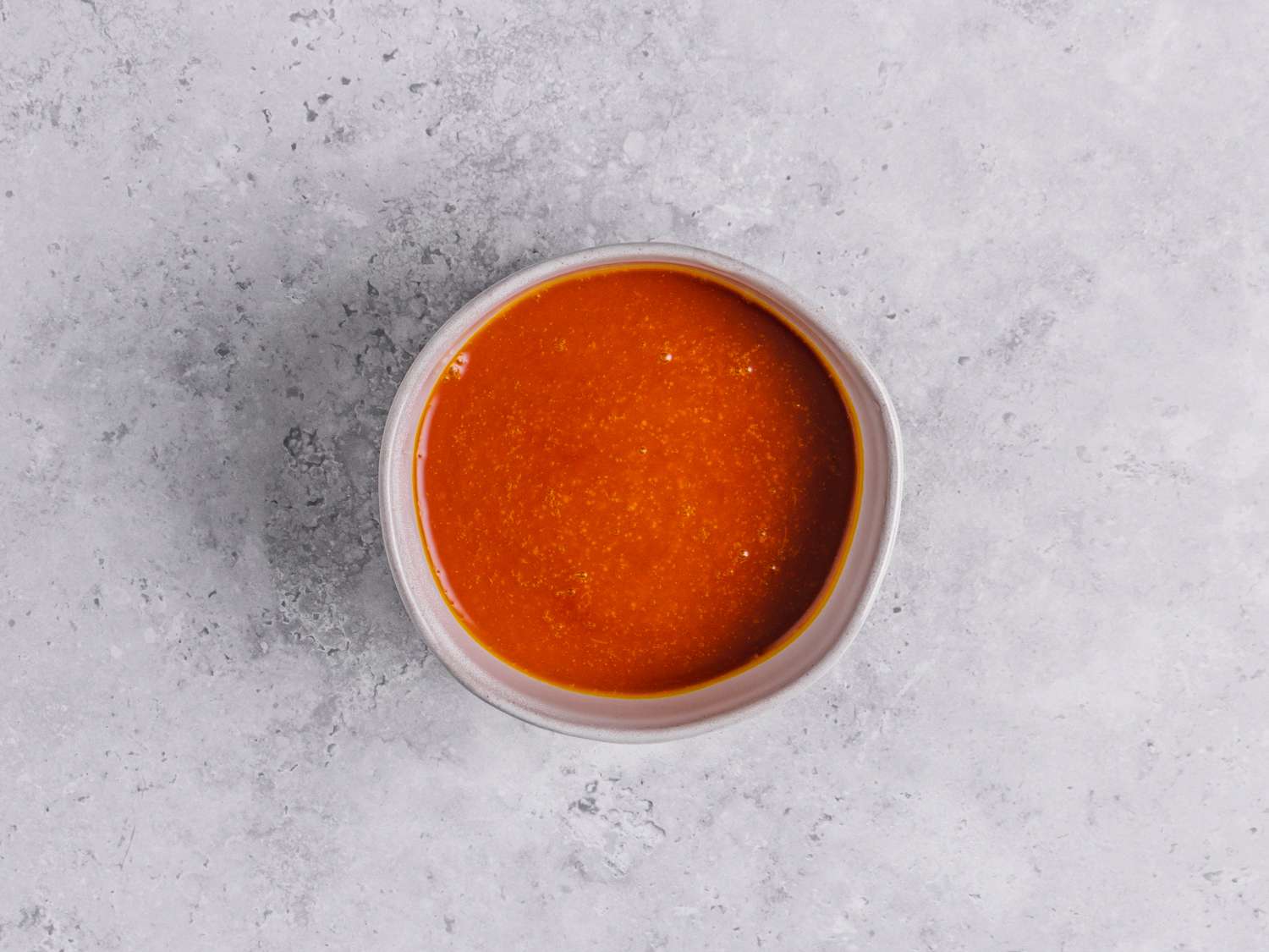 Palm oil in a bowl on a marbled grey surface