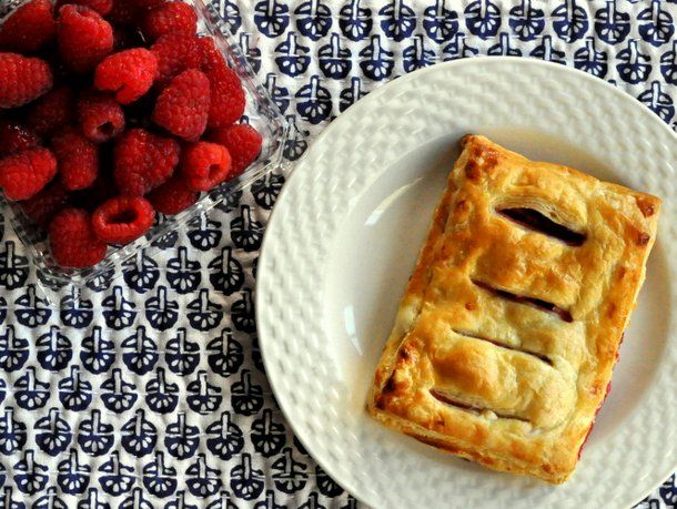 Overhead view of a raspberry jalousie, served on a small plate next to a clamshell container of raspberries.