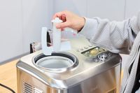 A hand holding a part of the Breville Smart Scoop Ice Cream Compressor over the device