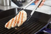 Person flipping pork chop on Staub Enameled Cast Iron Grill Pan