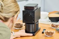 A person presses a button on the Fellow Ode Gen 2 Coffee Grinder