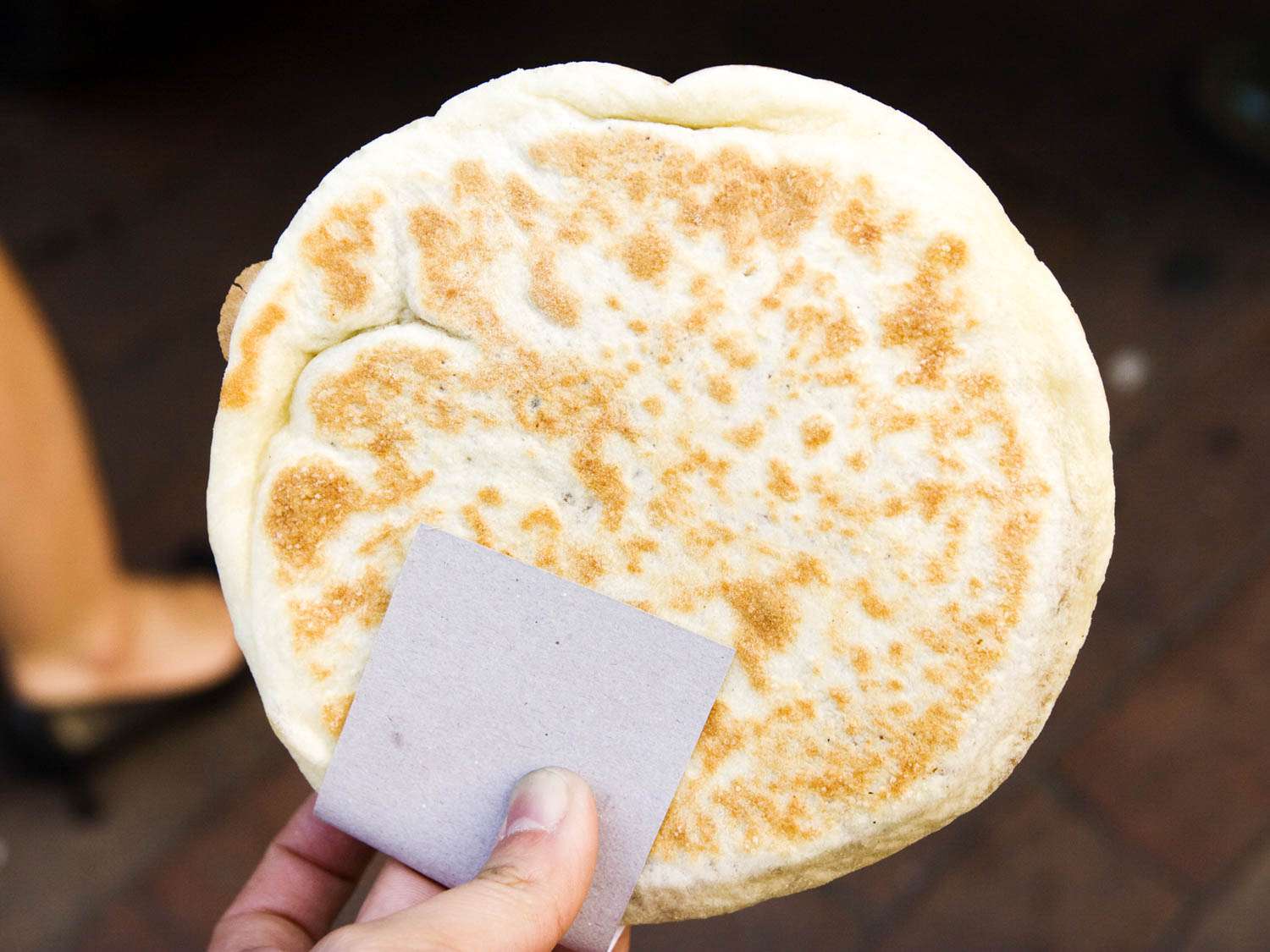 Someone holding a teok, a Korean pancake made from a sugary, yeasty wheat-based dough.