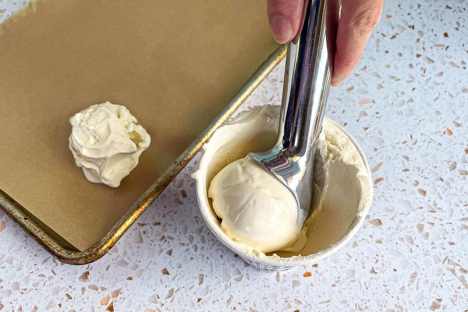 person using zeroll scoop to serve vanilla ice cream