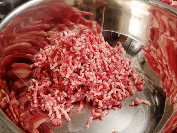A mixing bowl with a loose pile of coarsely ground beef.