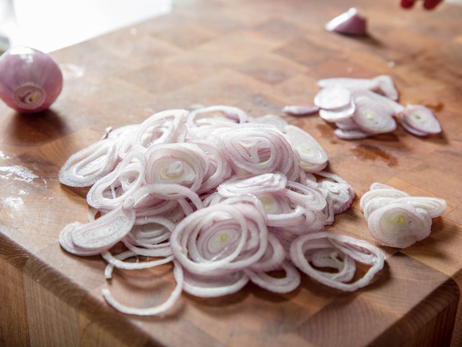 Sliced shallots on a cutting board for fried shallots.