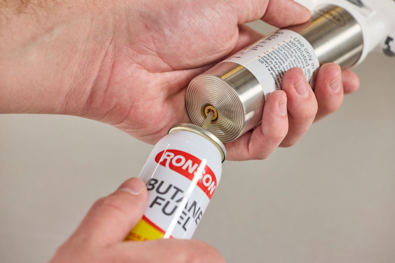 a person filling the rosle torch with butane