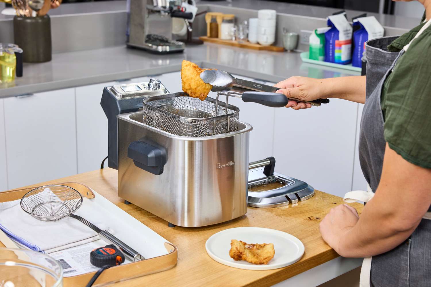 A person removing a fried item from the Breville BDF500XL Smart Fryer