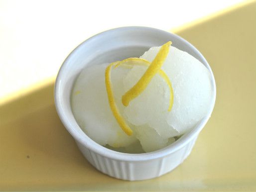 An overhead view of two scoops of lemon ice, garnished with lemon zest.