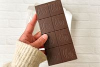 A hand holding the Theo Pure Dark 85% Chocolate Bar